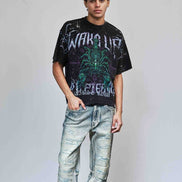 Person wearing a graphic t-shirt and distressed jeans against a plain background
