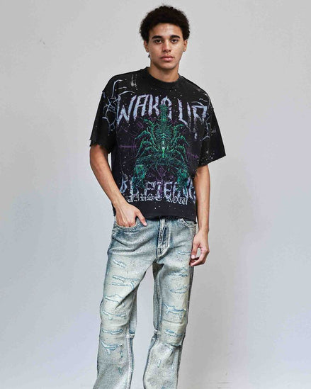 Person wearing a graphic t-shirt and distressed jeans against a plain background