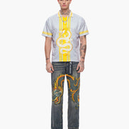Man wearing a patterned shirt and jeans with dragon design on a white background