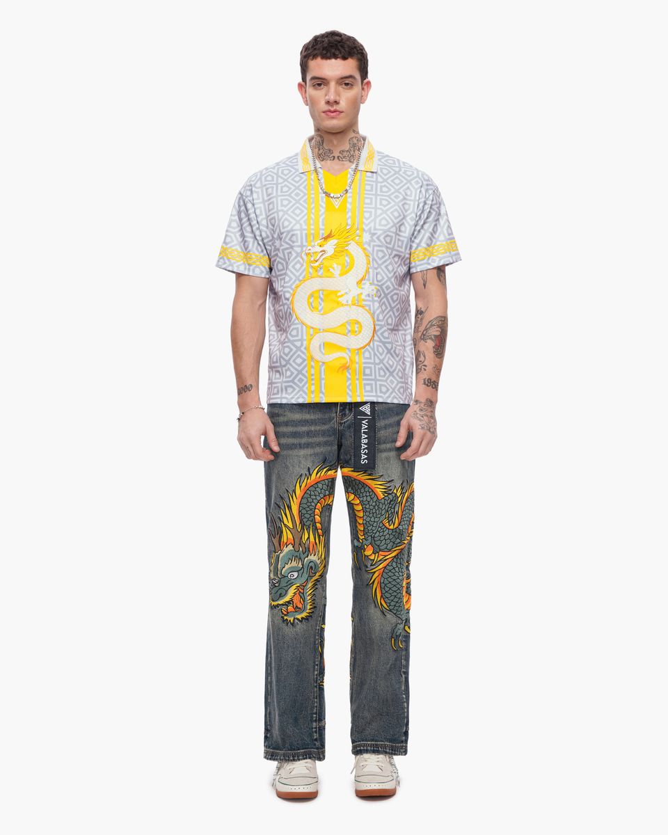 Man wearing a patterned shirt and jeans with dragon design on a white background