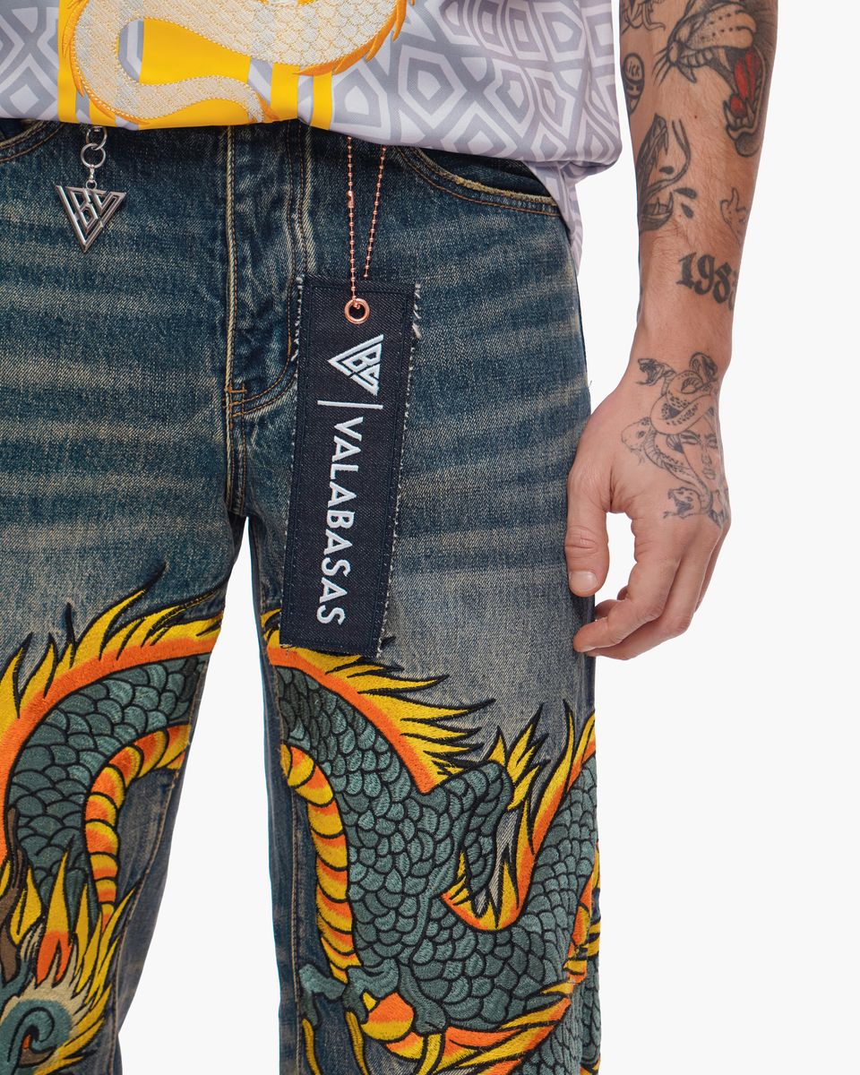 Denim pants with dragon design and Valabasas tag, person wearing them.
