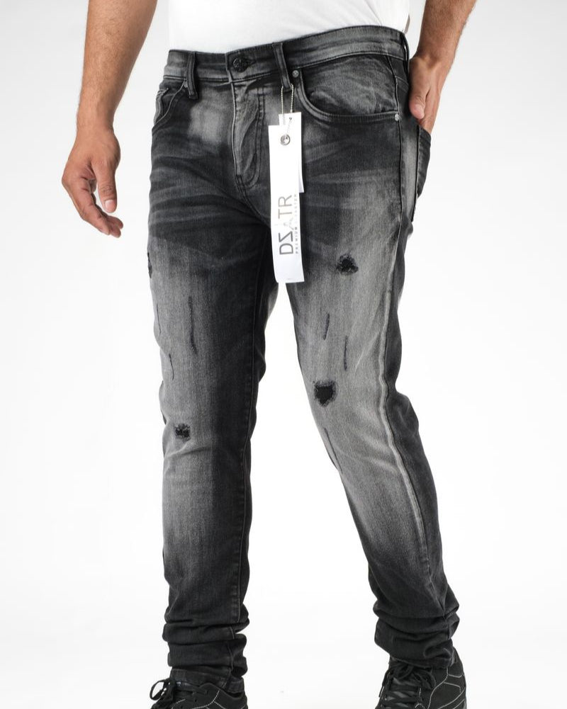 Person wearing black distressed jeans with a visible brand tag on a white background