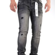 Person wearing gray distressed jeans with a brand tag, standing against a white background