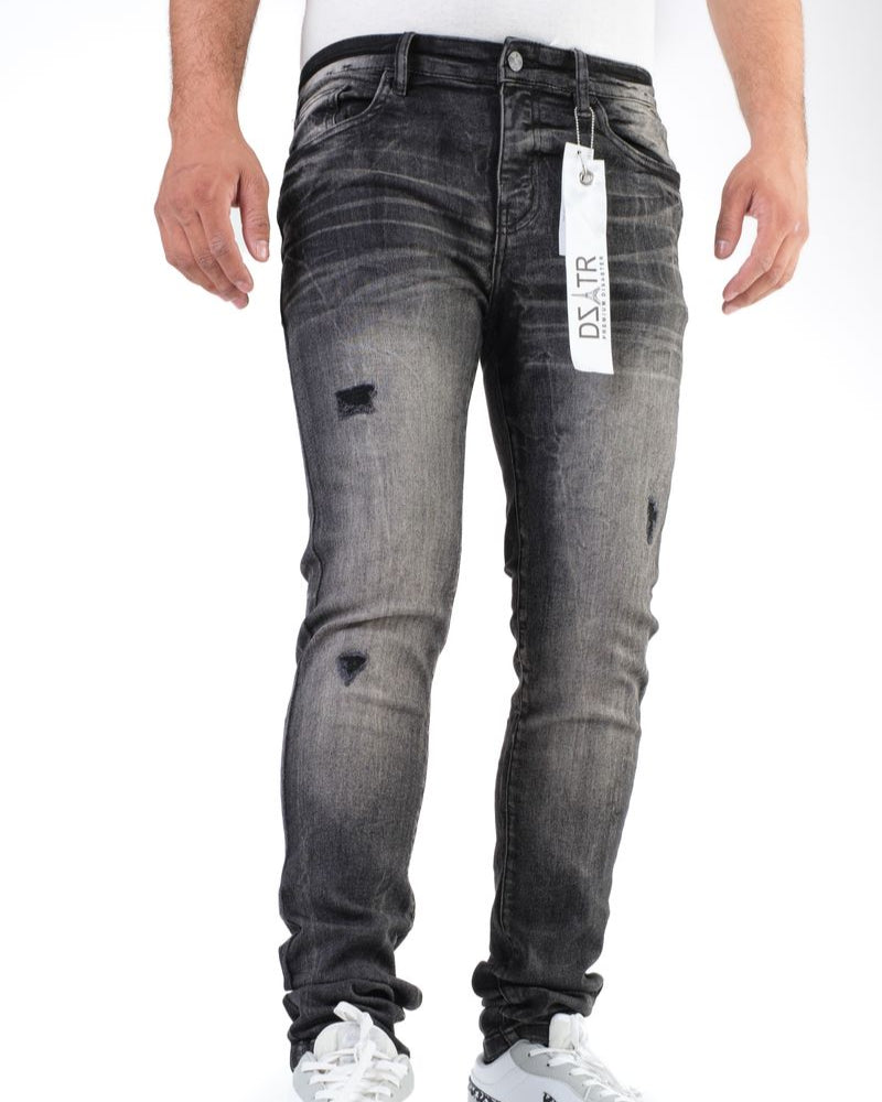 Person wearing gray distressed jeans with a brand tag, standing against a white background
