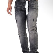 Person wearing black distressed jeans with a tag, standing on a white background