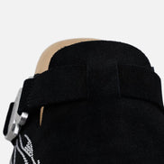 Black boot with a strap and decorative design on a white background