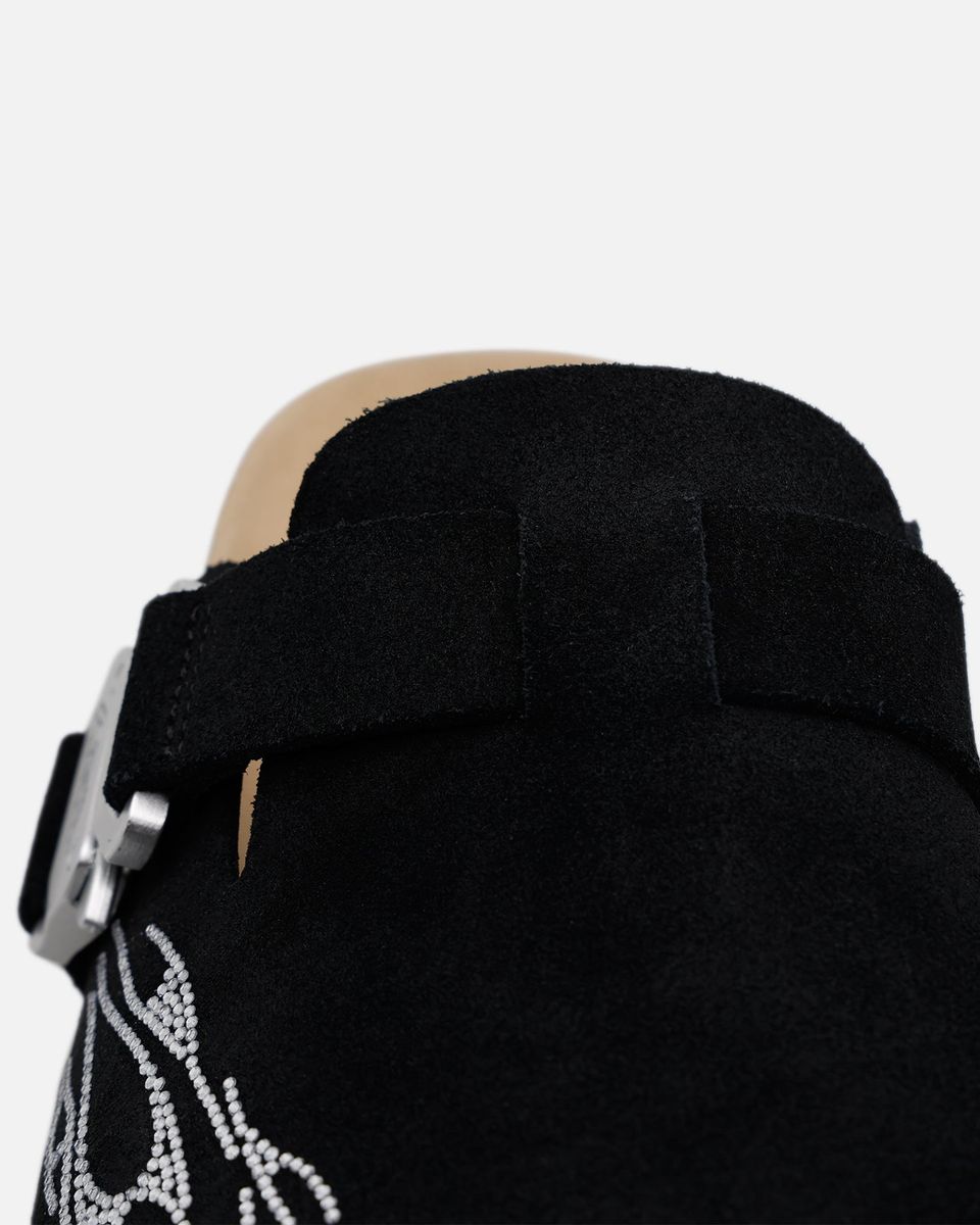 Black boot with a strap and decorative design on a white background