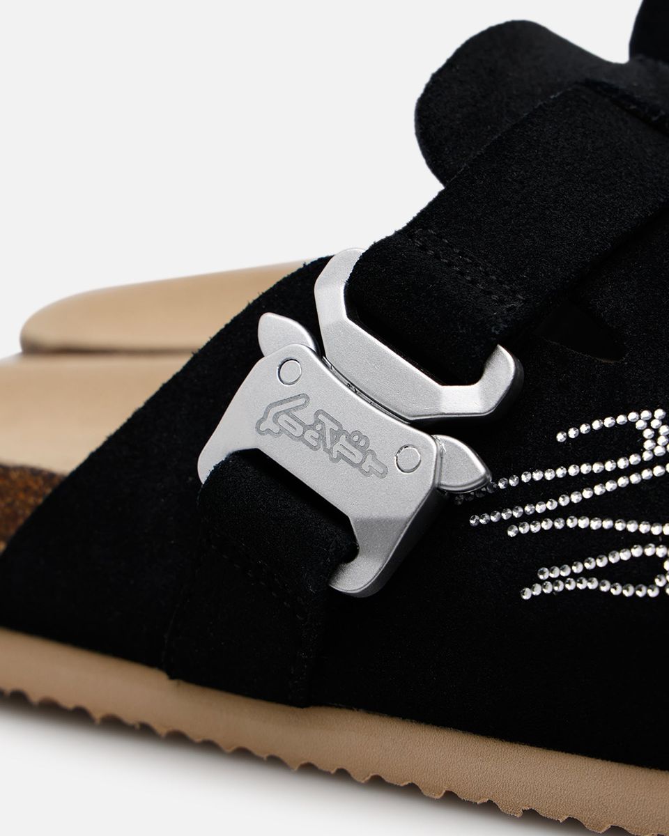 Black sneaker with a silver bottle opener attached to the tongue on a white background