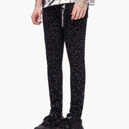 Black pants with white speckles worn by a person on a white background