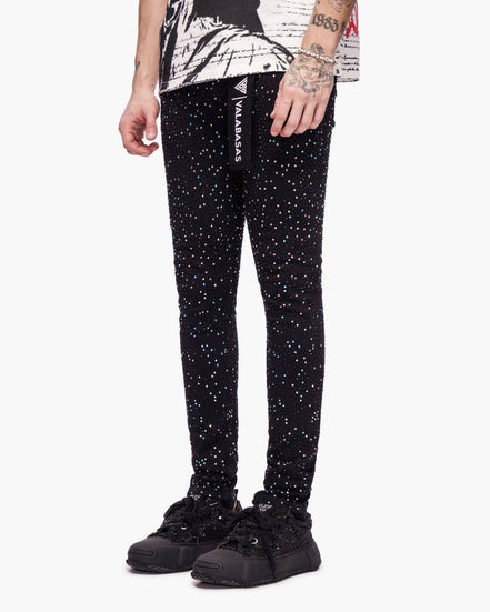 Black pants with white speckles worn by a person on a white background