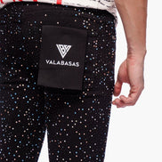 Person wearing black pants with multicolor dots and a black waist bag with 'VALABASAS' branding.