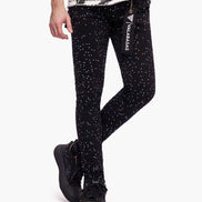 Person wearing black leggings with white speckles and a visible brand logo on a white background