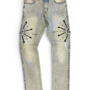 Distressed denim jeans with embellishments on a white background