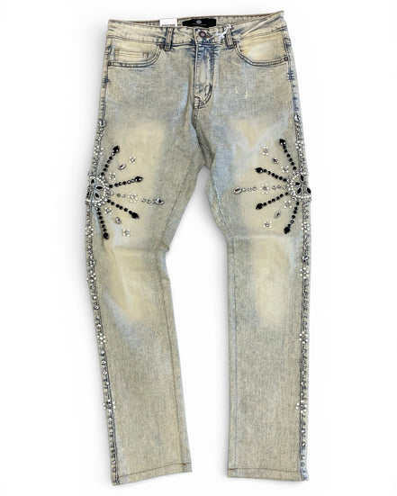 Distressed denim jeans with embellishments on a white background