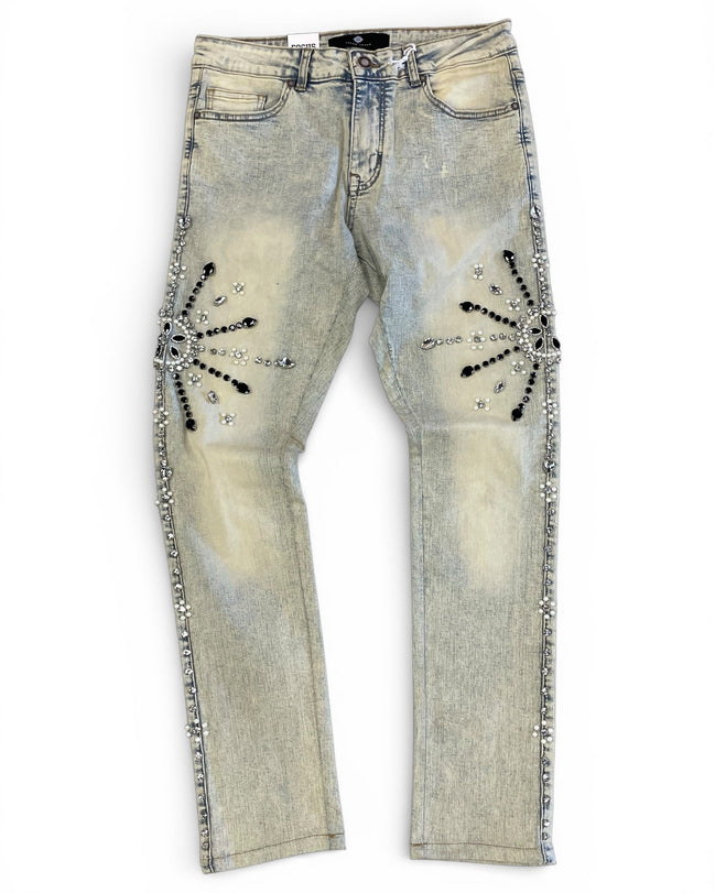 Distressed denim jeans with embellishments on a white background