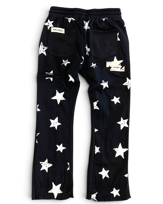 Black pants with an all-over white star pattern, featuring an elastic waistband, side cargo pockets, and elastic cuffs at the ankles, shown flat on a white background.