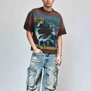 Person wearing a graphic t-shirt and distressed jeans against a plain background