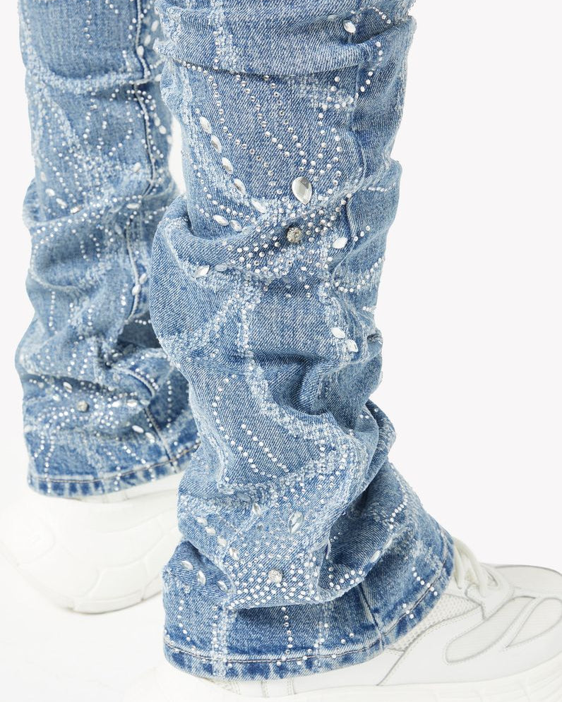 Blue jeans with rhinestone embellishments worn with white sneakers on a white background