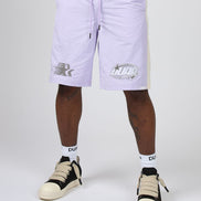 A person wearing light lavender athletic shorts with white socks and beige-and-black sneakers, shown from the waist down against a plain light gray studio background.