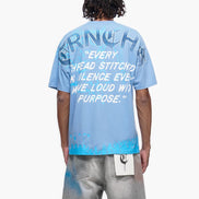 Person wearing a blue t-shirt with text on the back, standing against a white background