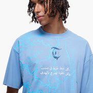 Person wearing a blue t-shirt with Arabic text and graphics on a white background