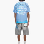 Person wearing a blue t-shirt with text and gray shorts on a white background