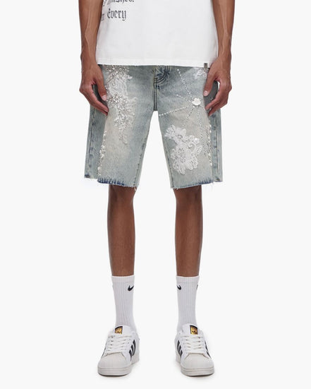 Person wearing light blue denim shorts with white floral patterns on a white background