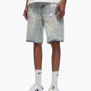 Person wearing light denim shorts with sequin details on a white background