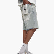 Person wearing light gray distressed denim shorts with a white background
