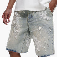 Denim shorts with floral embroidery and a white t-shirt worn by a person on a plain background