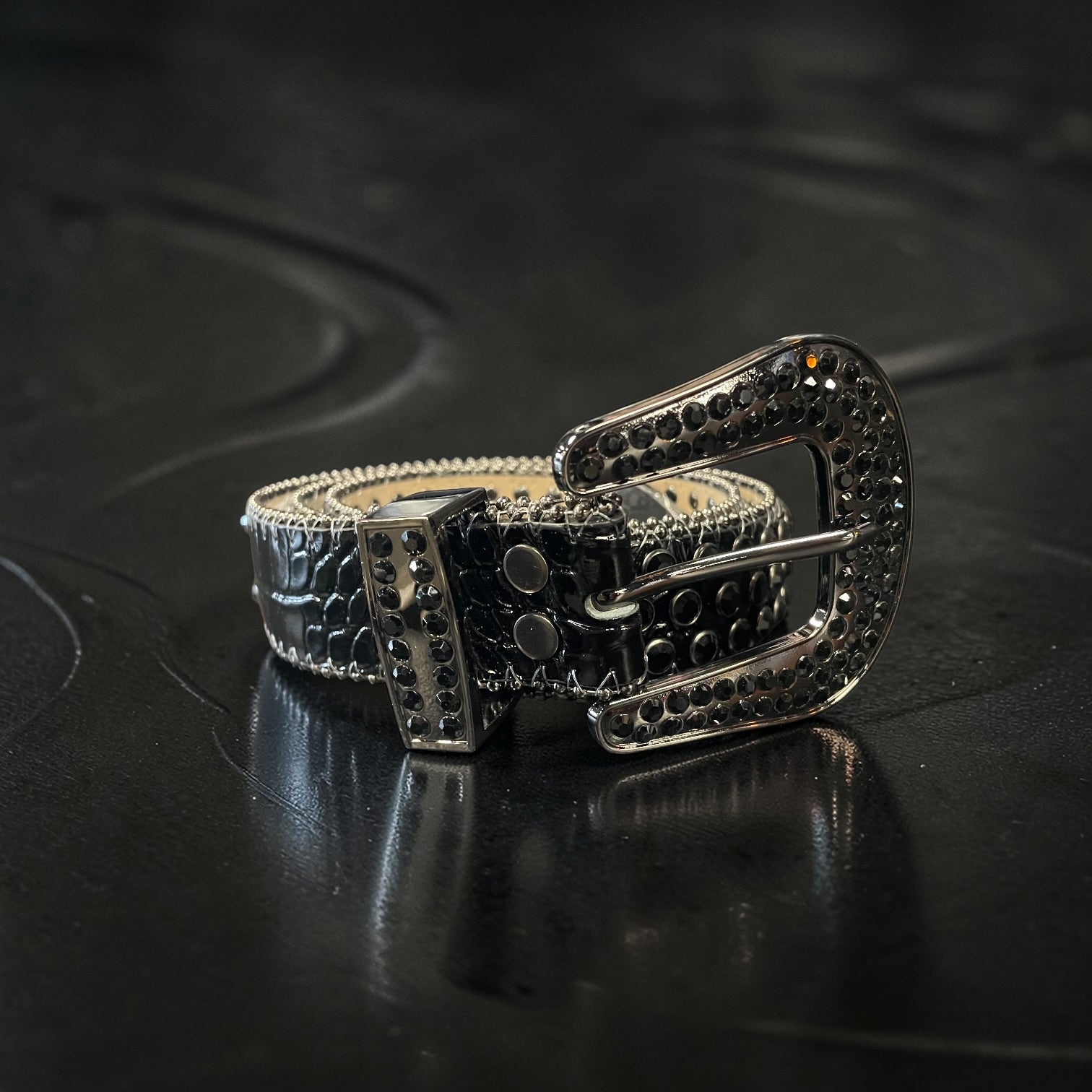 Silver belt with intricate design on a dark textured surface