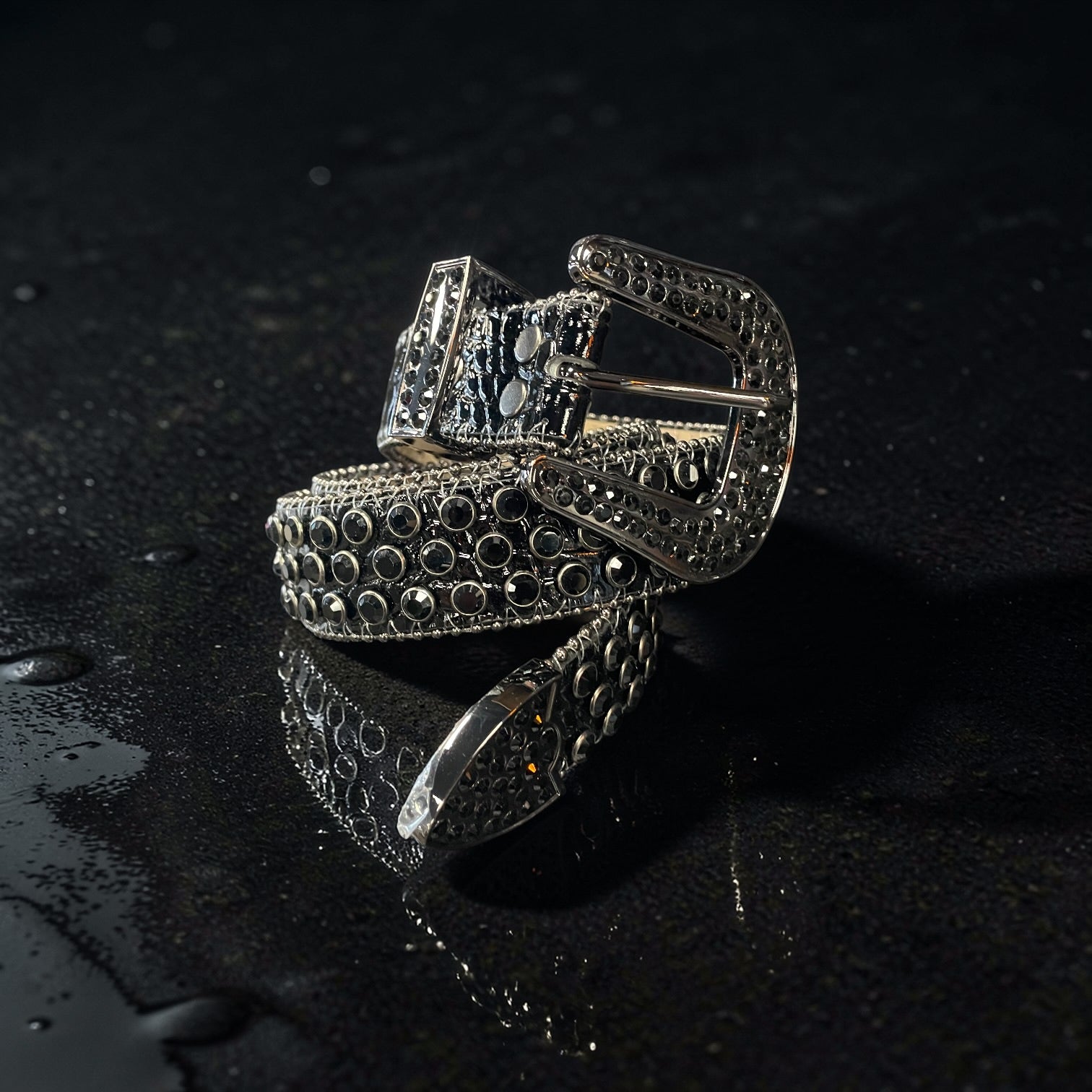 Silver and black belt with intricate design on a dark surface