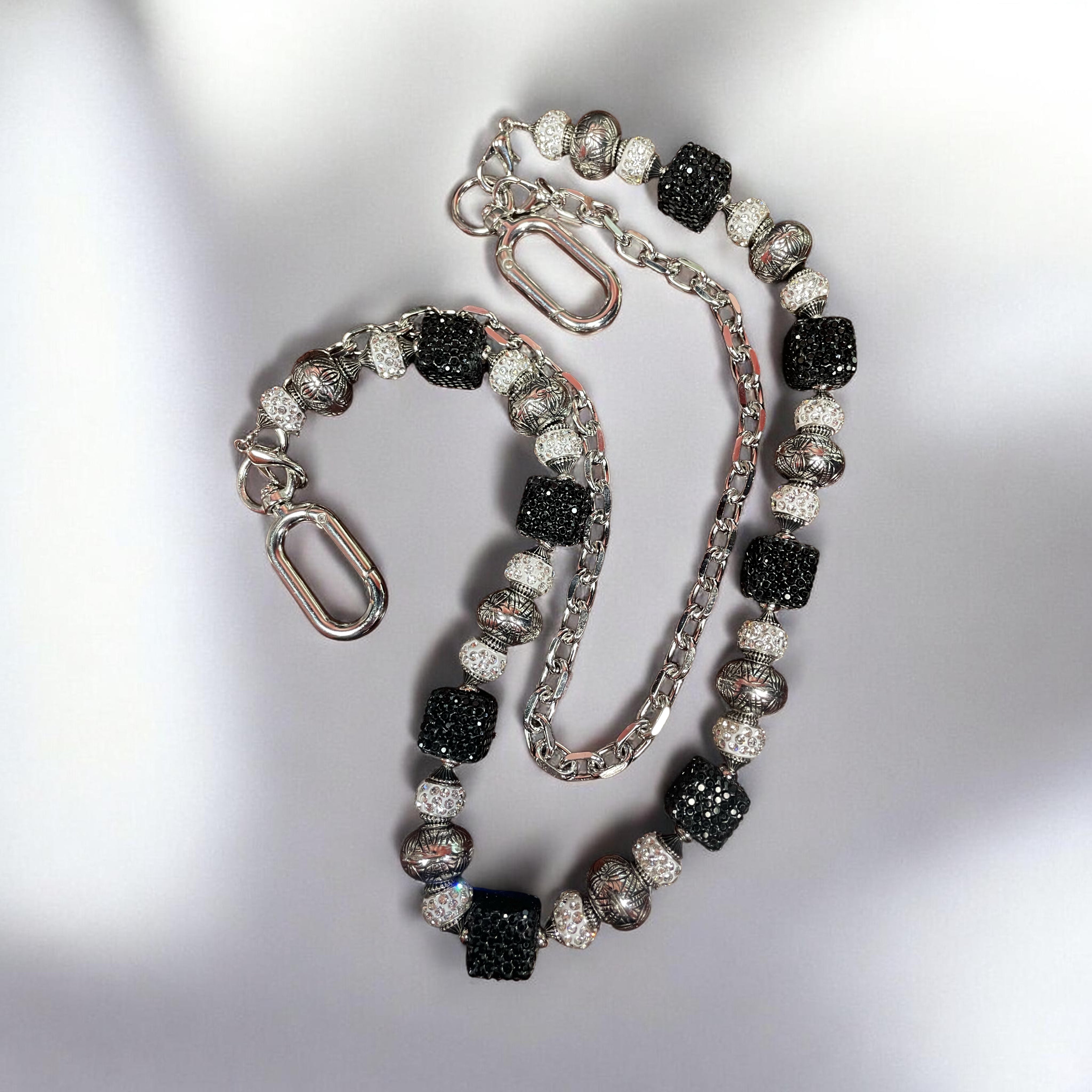 Beaded chain with black and silver gems on a light gray background