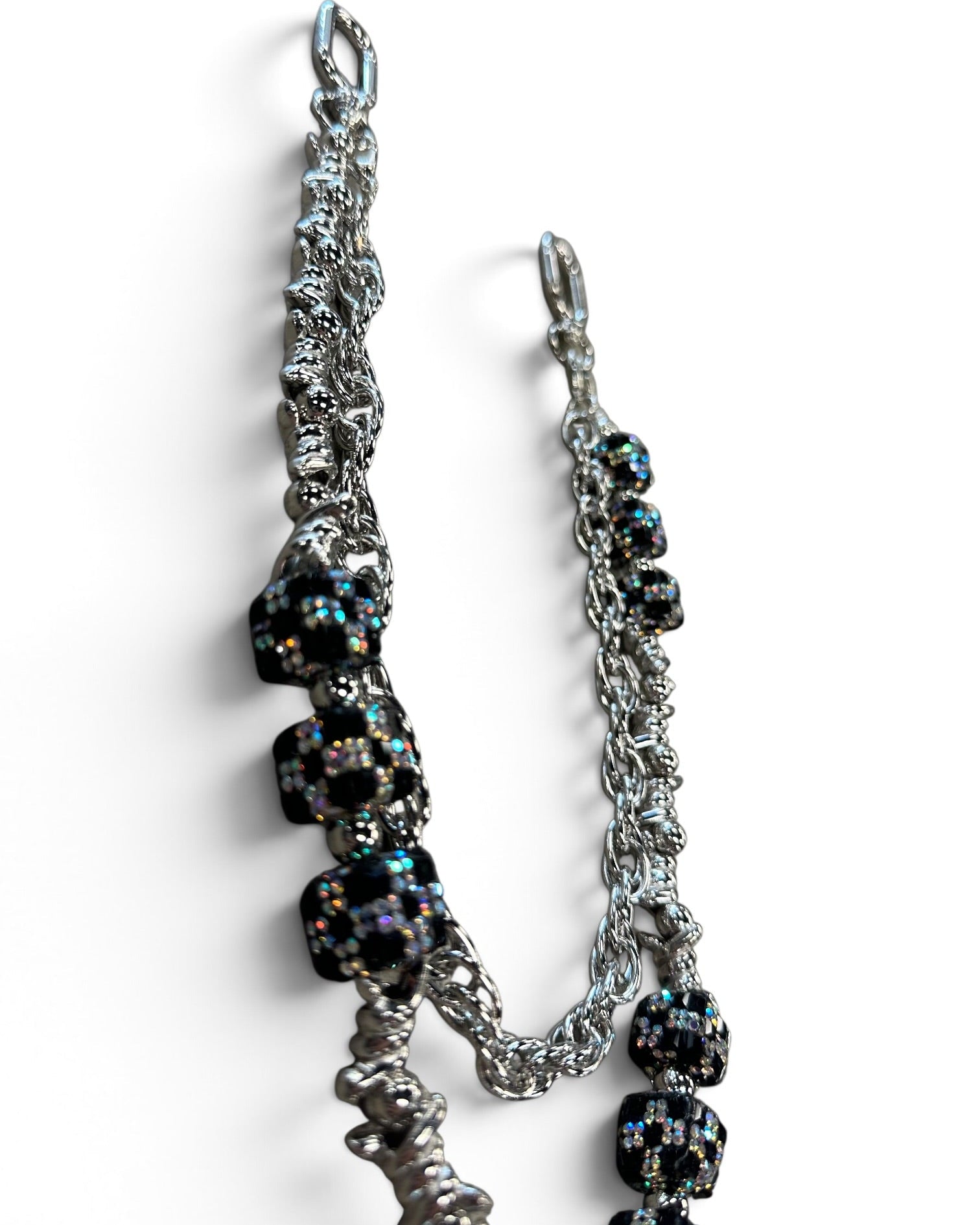 A silver-toned chain accessory with multiple black faceted beads that shimmer with iridescent rainbow reflections, photographed on a clean white background.