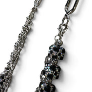 A close-up of a silver-toned chain strap with a decorative dangling section featuring black faceted rhinestone beads and silver hardware, shown on a plain white background.