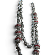 A silver-toned chain necklace featuring textured spiral beads with red inlay, displayed on a clean white background.