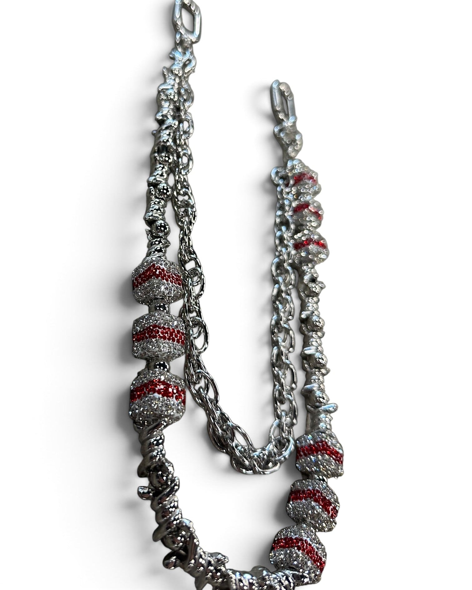A silver-toned chain necklace featuring textured spiral beads with red inlay, displayed on a clean white background.