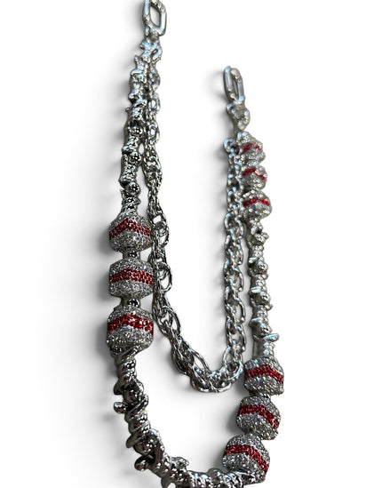 A silver-toned chain necklace featuring textured spiral beads with red inlay, displayed on a clean white background.