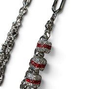 A silver-toned metal chain accessory with three decorative bell-shaped charms covered in clear rhinestones and accented with horizontal red crystal stripes, shown on a white background.
