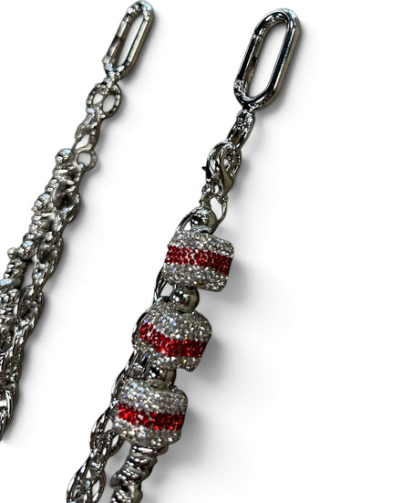 A silver-toned metal chain accessory with three decorative bell-shaped charms covered in clear rhinestones and accented with horizontal red crystal stripes, shown on a white background.
