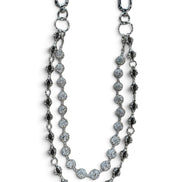 A silver-toned double-strand chain accessory featuring textured oval links, round pavé-style discs, and elongated drop links, displayed on a clean white background.
