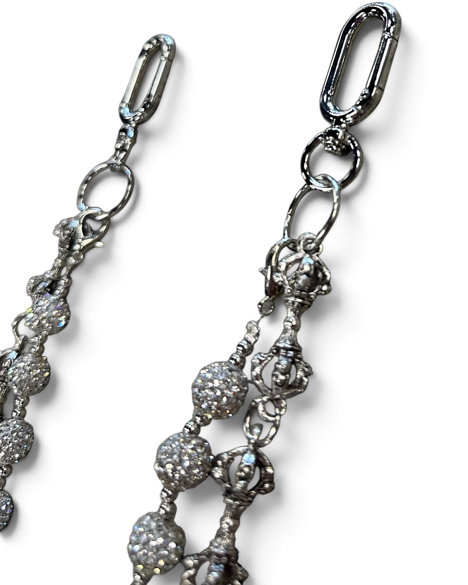 Close-up of a silver-toned jewelry accessory with a lobster clasp and dangling beaded chain details on a white background.