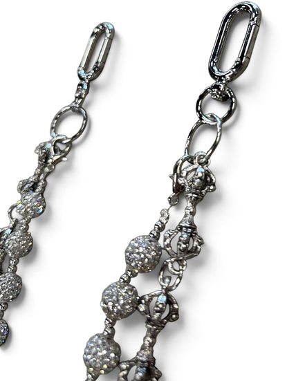 Close-up of a silver-toned jewelry accessory with a lobster clasp and dangling beaded chain details on a white background.