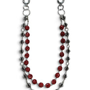 A silver-toned chain accessory featuring a central strand of faceted red beads and flanking strands of textured silver and dark metallic links, displayed on a clean white background.