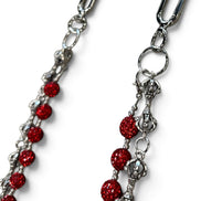 A close-up of a silver-toned metal chain accessory with multiple strands of round, glittery red beads, shown on a plain white background.