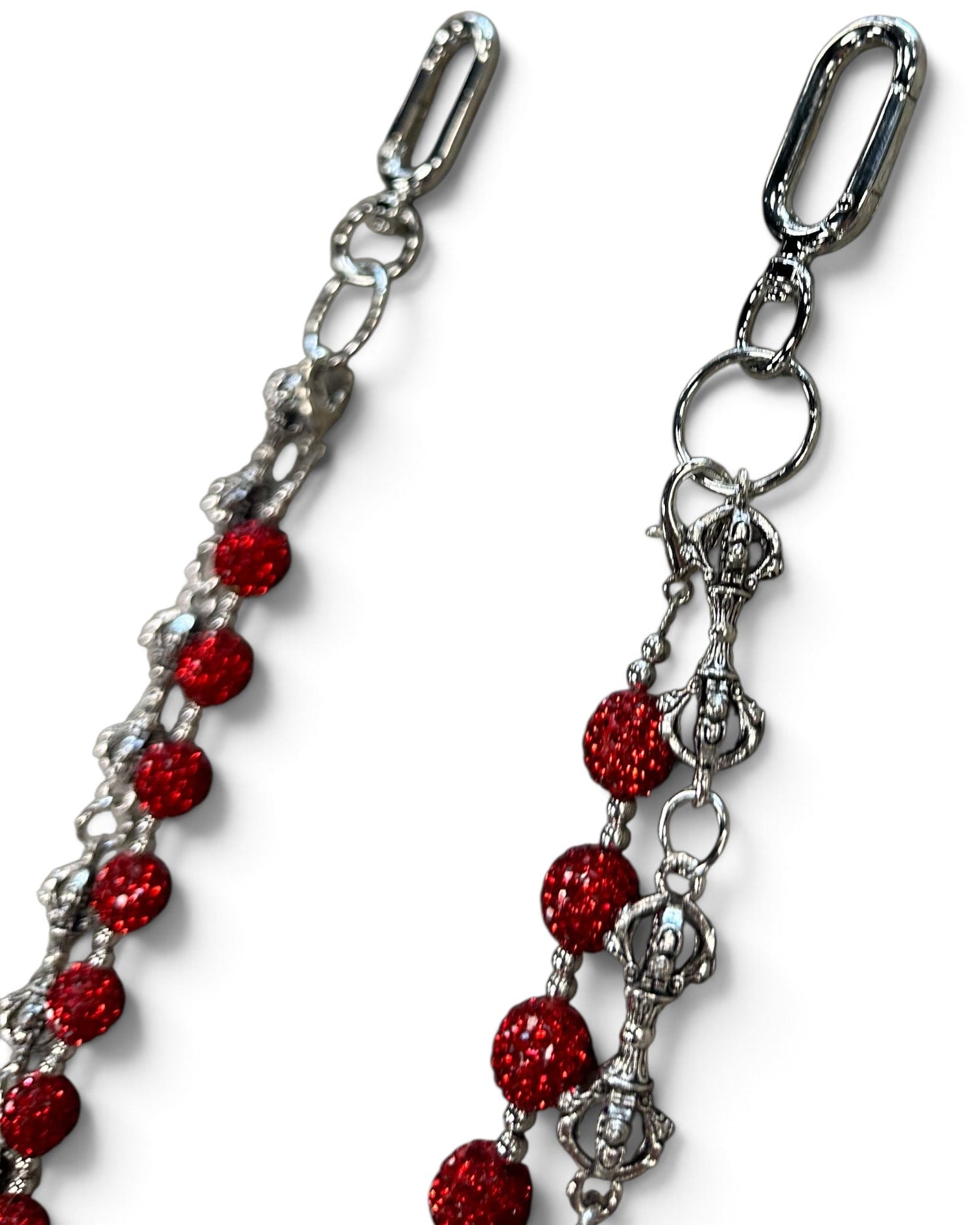 A close-up of a silver-toned metal chain accessory with multiple strands of round, glittery red beads, shown on a plain white background.