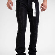 Person wearing black jeans with a tag, standing against a white background