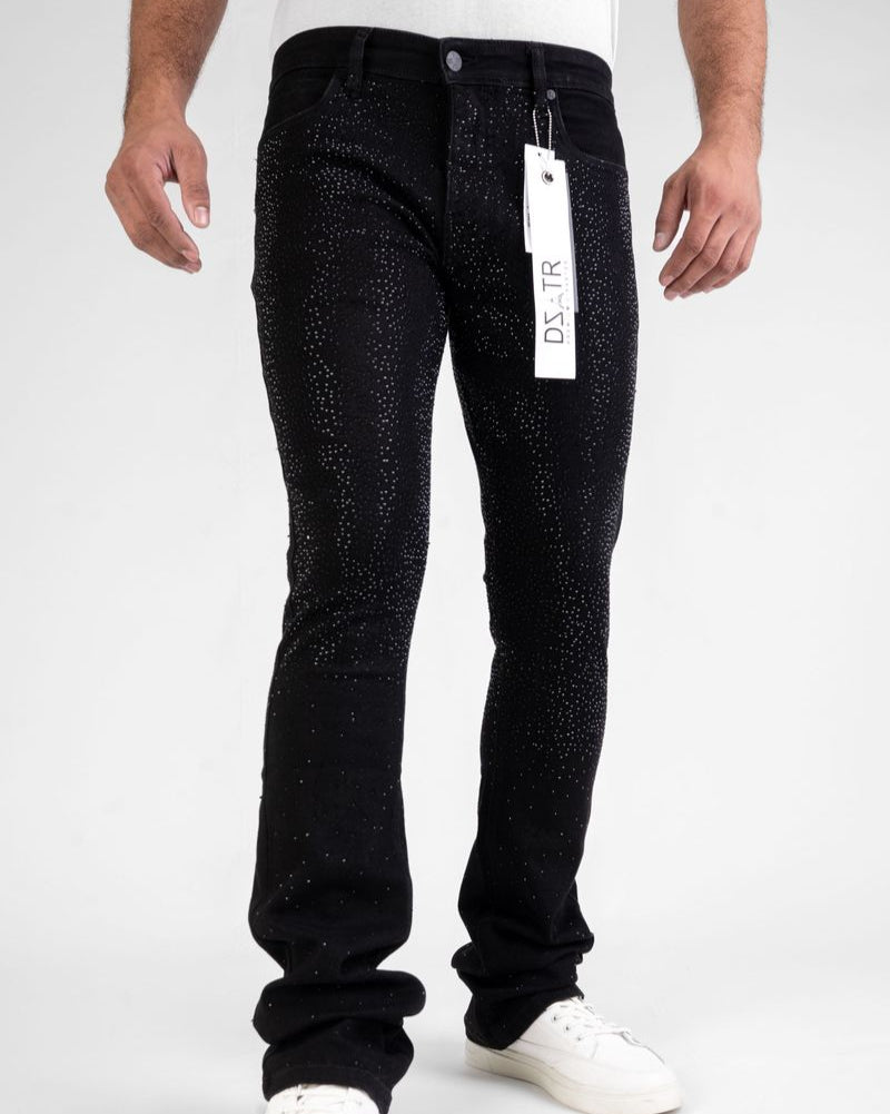 Person wearing black jeans with a tag, standing against a white background