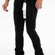 Person wearing black jeans with a tag, standing against a white background