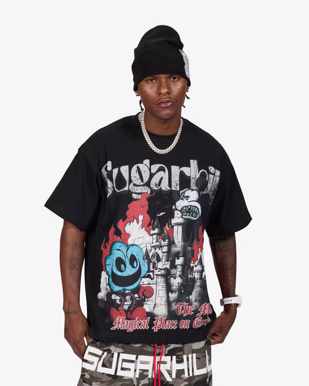 A man wearing a black beanie, a black Sugarhill Gang graphic t-shirt, and camouflage shorts with 'SUGARHILL' printed on the front, standing against a light gray background.
